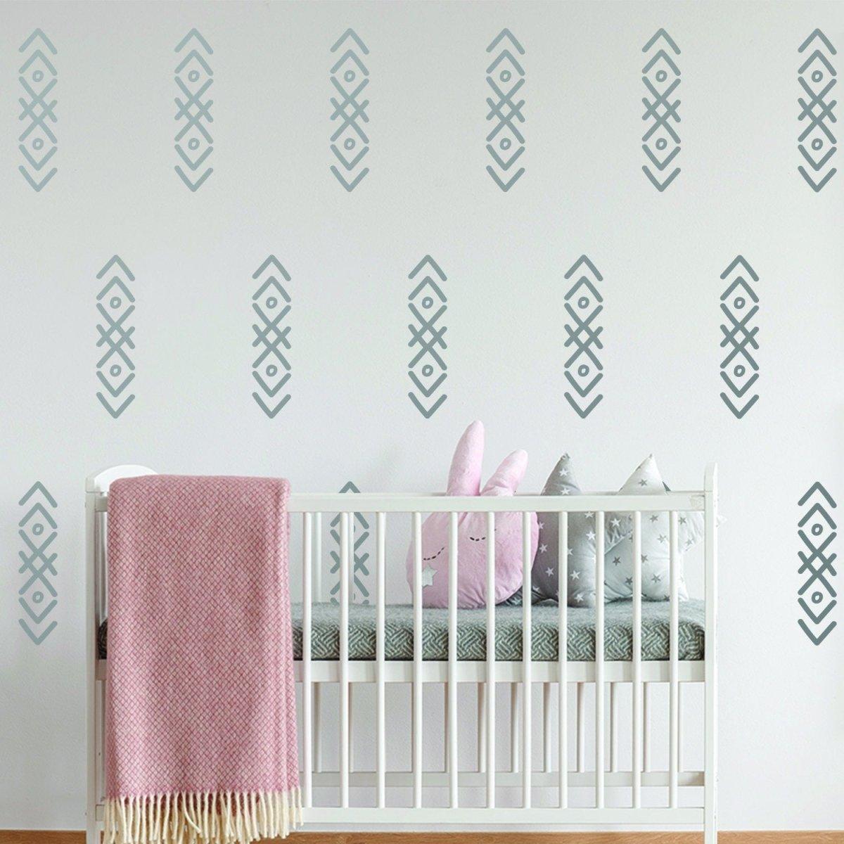 Stylish arrow wall stickers in a nursery with crib, blanket, and plush toys, adding charm and whimsy to the decor.