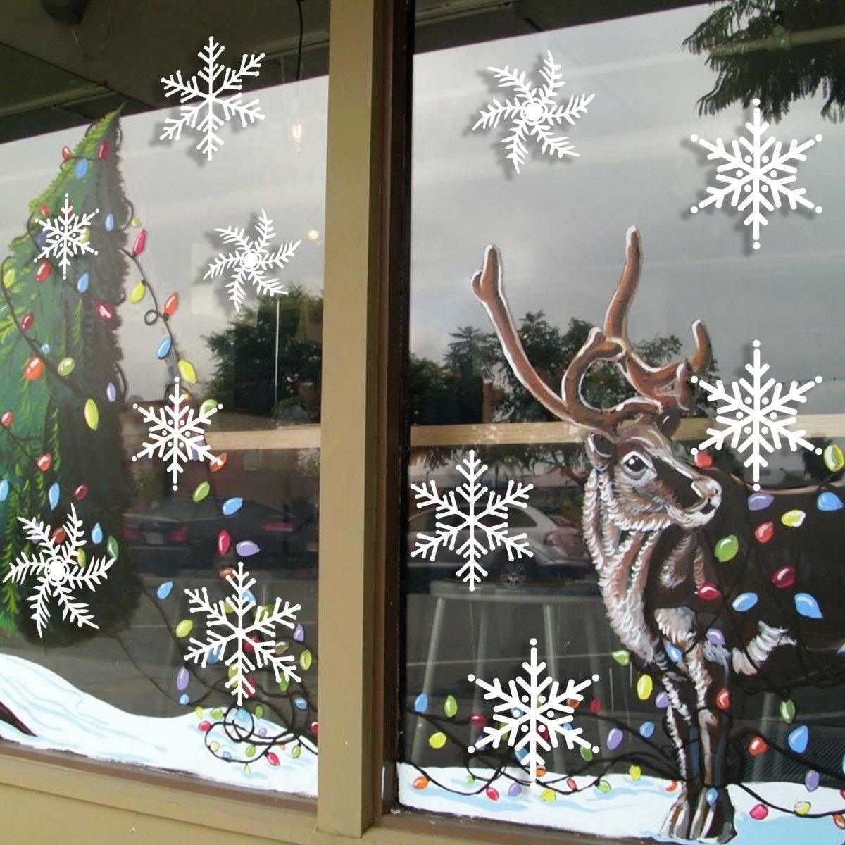 Festive window decoration with snowflake stickers, reindeer, Christmas tree, and colorful lights.