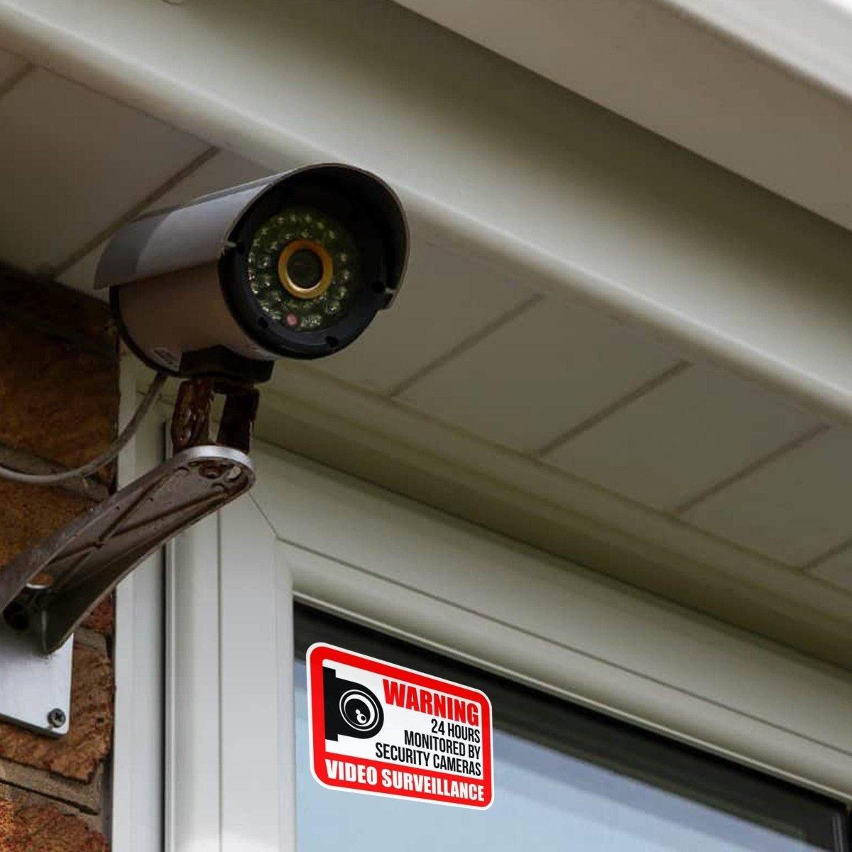 Video surveillance camera with warning sign posted on window for enhanced home security.