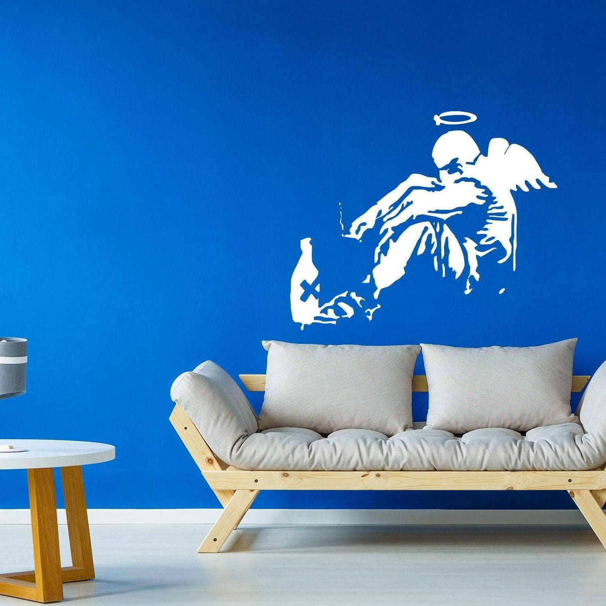 Banksy Fallen Angel wall sticker on blue wall, adding urban art flair to modern living space.