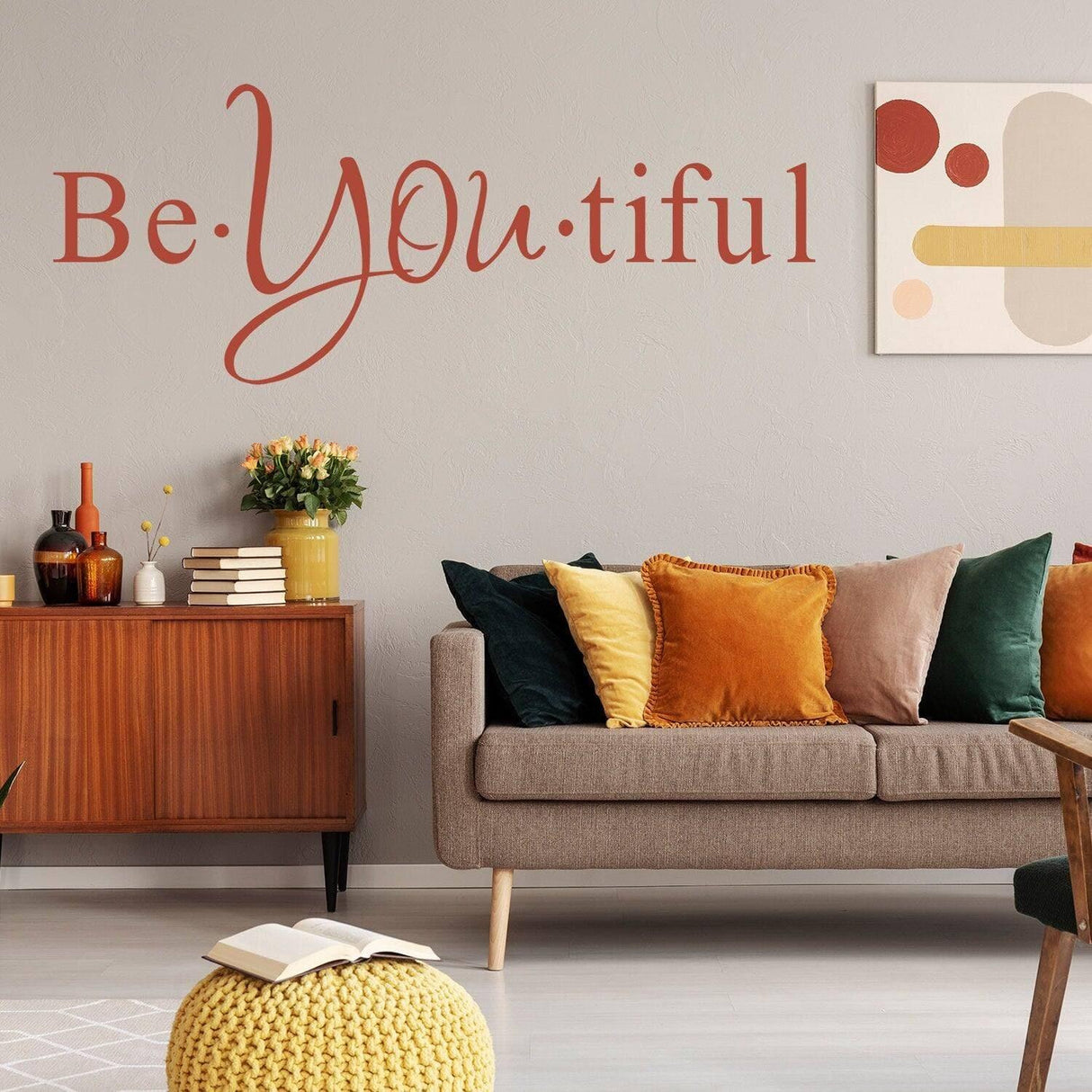 Motivational wall art saying 'Be YOU tiful' above a cozy couch and decor in a modern interior.