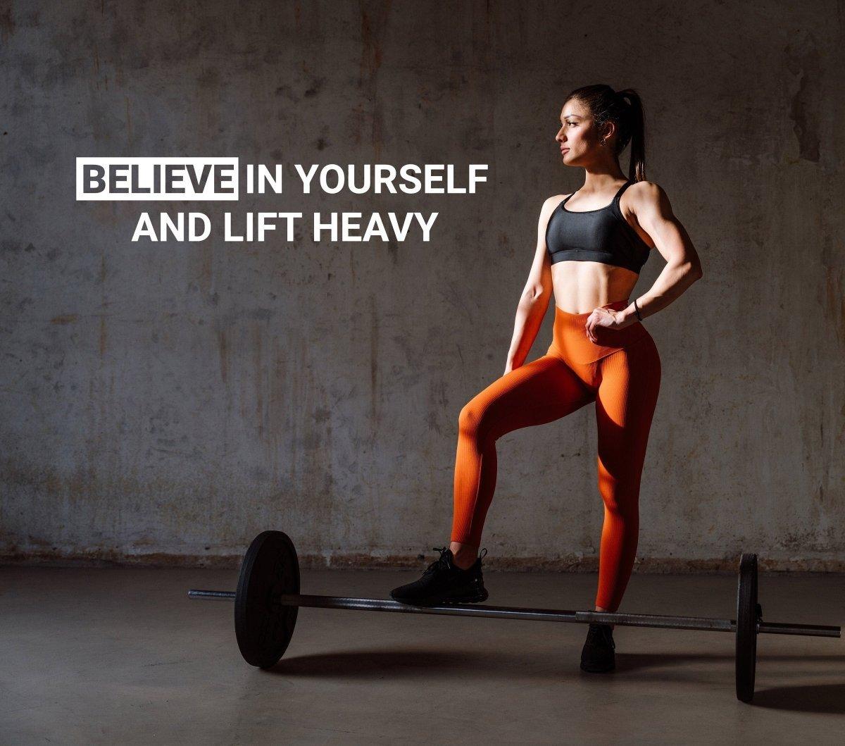 Motivational gym wall decal featuring the text 'Believe in Yourself and Lift Heavy' on a fitness model.
