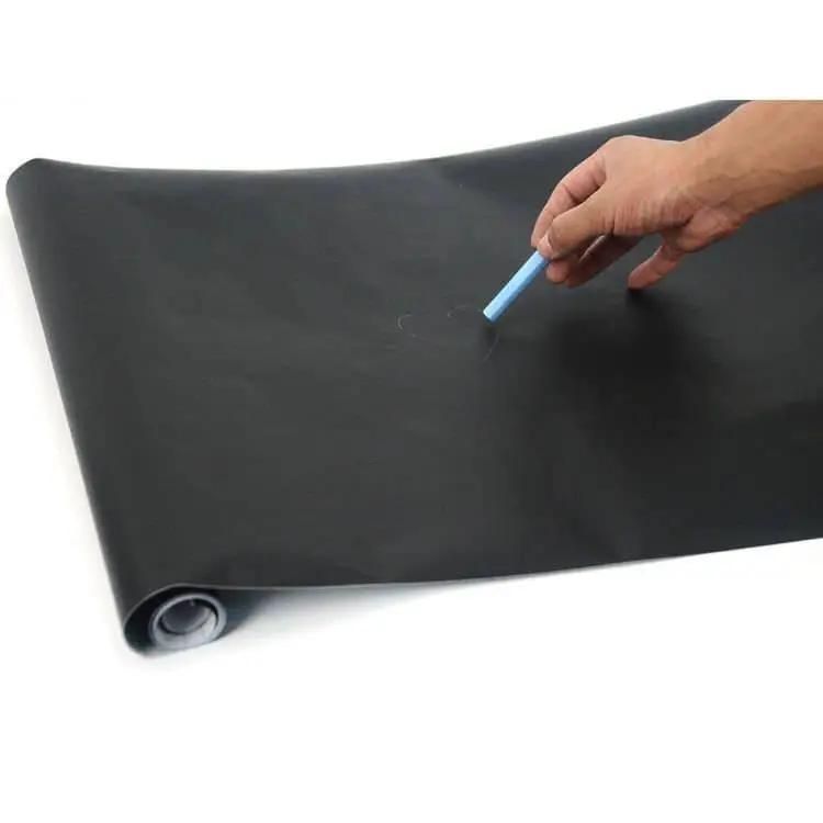 Person drawing with blue chalk on a smooth black chalkboard wall sticker.