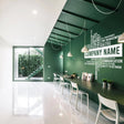 Modern office interior featuring a personalized wall decal with business name on vibrant green wall.