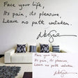 Inspirational handwritten quote wall decal on display above a modern sofa with decorative pillows.