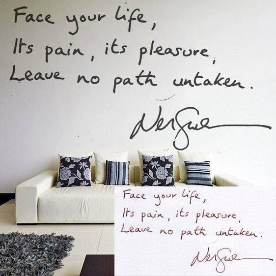 Inspirational handwritten quote wall decal on display above a modern sofa with decorative pillows.