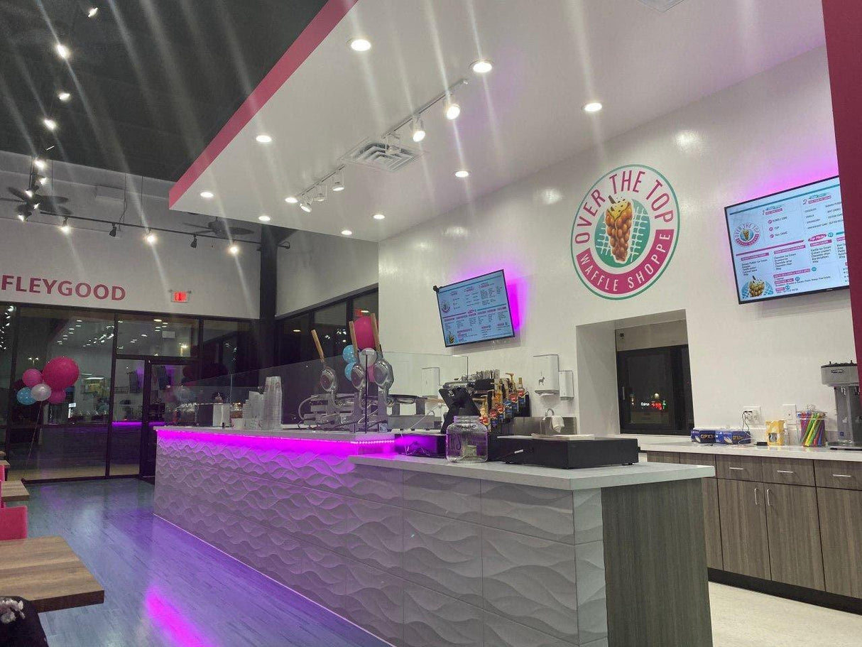 Interior view of Over The Top Waffle Shop with modern decor and vibrant lighting.
