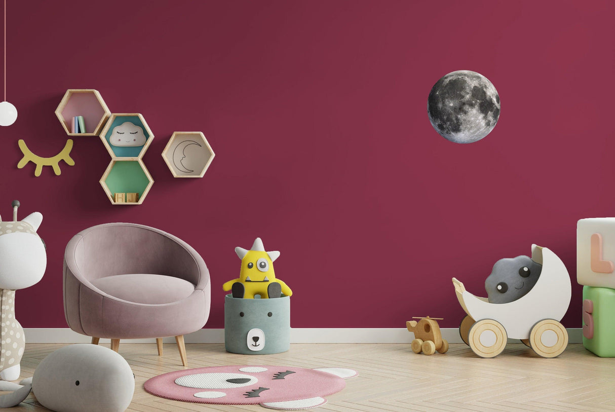 Lunar cycle wall sticker decorating a kid's room, featuring a full moon on a magenta wall with playful toys.
