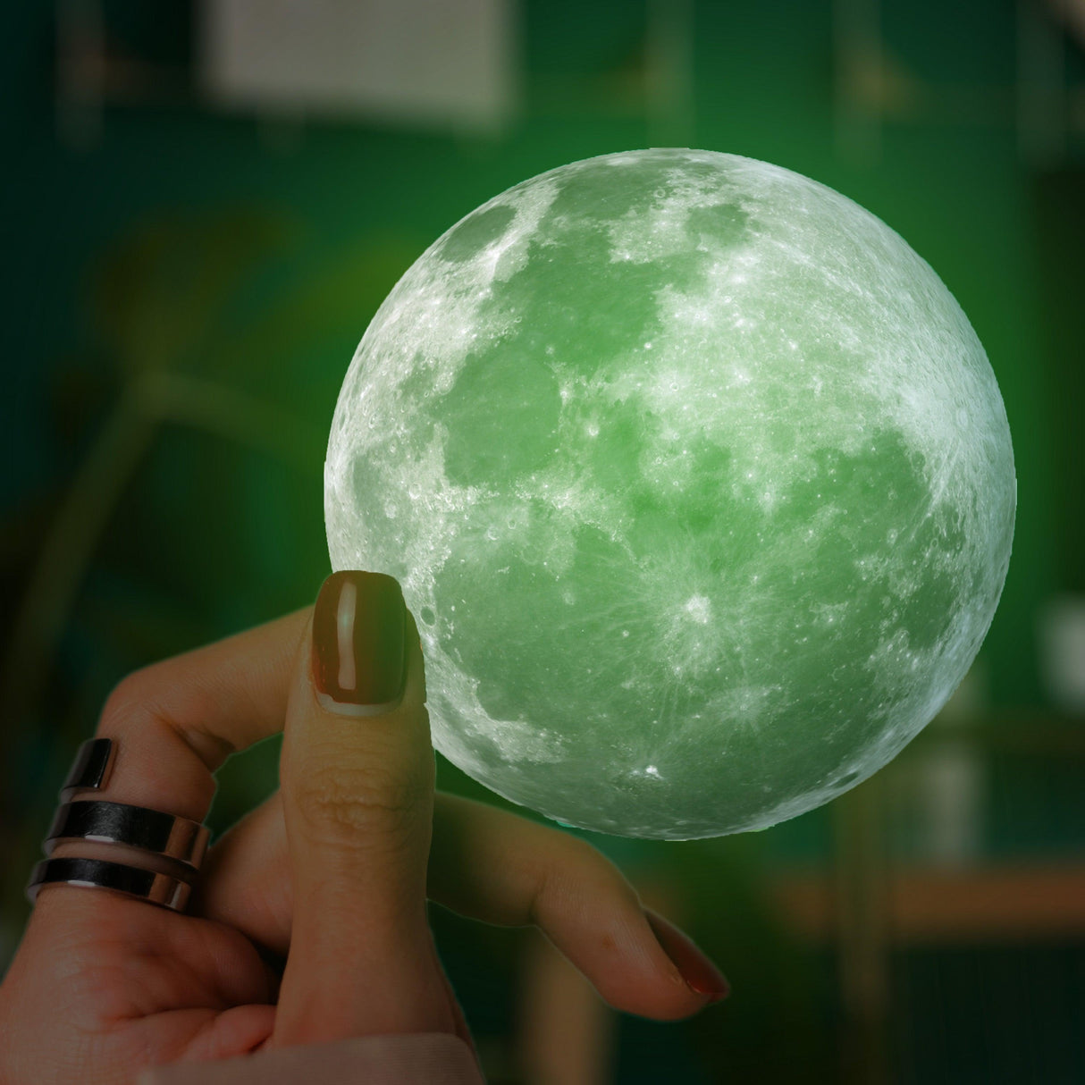 Hand holding a glowing green moon decal, perfect for adding unique decor to laptops and other surfaces.