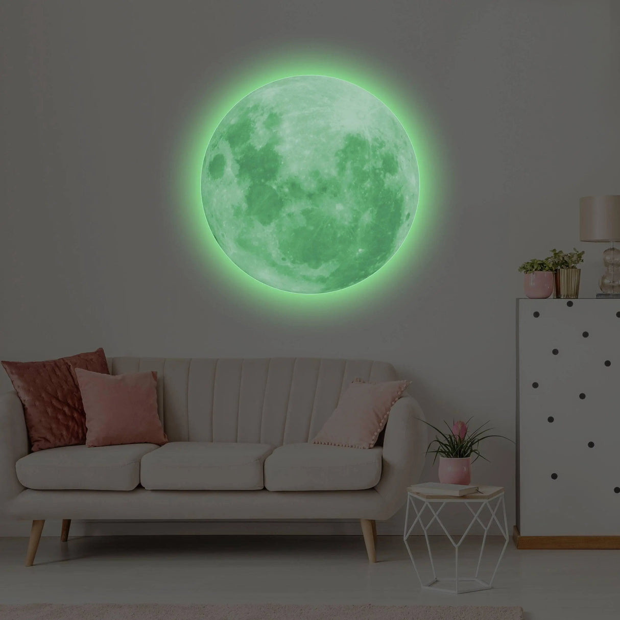 Glow in the dark moon wall decal illuminating a cozy living room with pink accents.