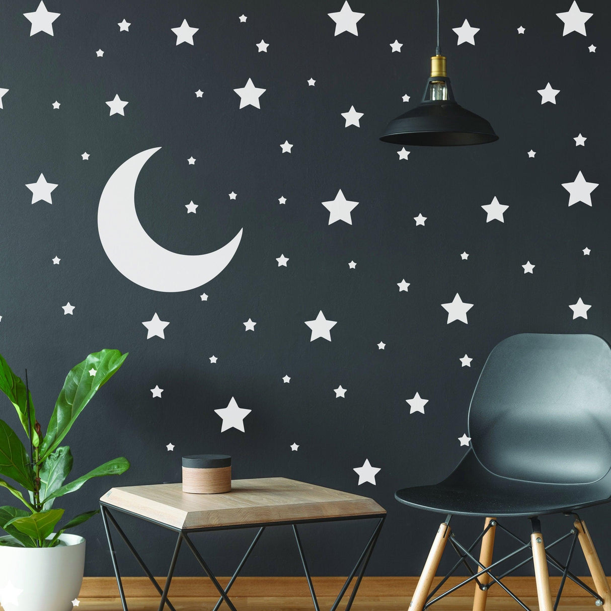 White stars and crescent moon wall stickers in a kid's room with a dark wall and modern decor.