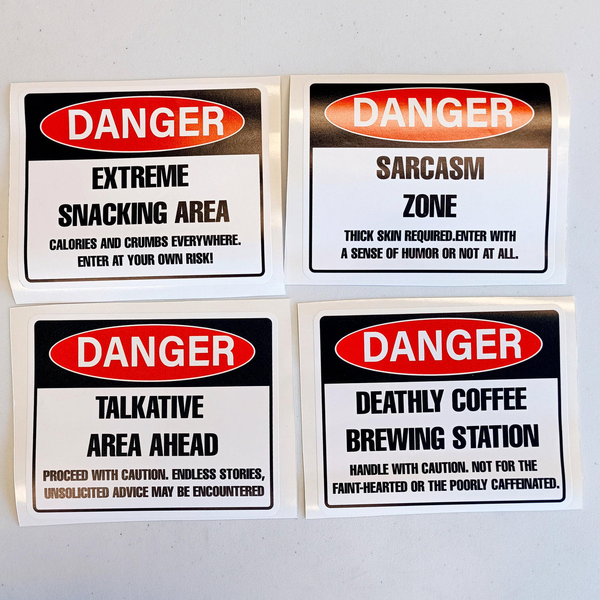 Humorous danger warning label decals featuring snacking, sarcasm, talkative area, and coffee brewing signs.