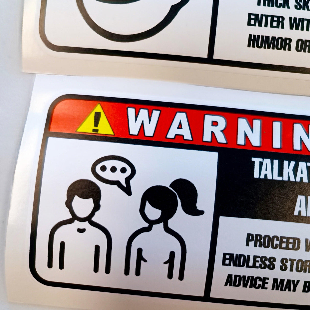 Funny warning label sticker depicting two talkative characters with a speech bubble, perfect for kitchens and offices.