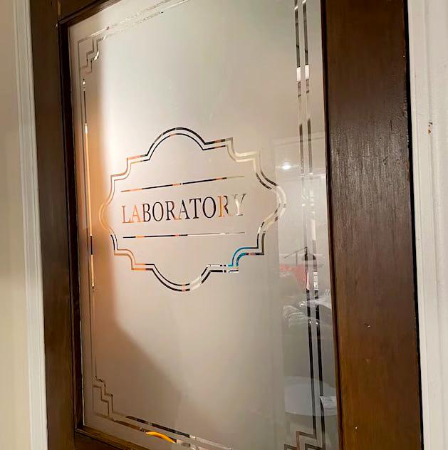 Elegant frosted mirror decal on a laboratory door, featuring a decorative border and the word 'LABORATORY'.