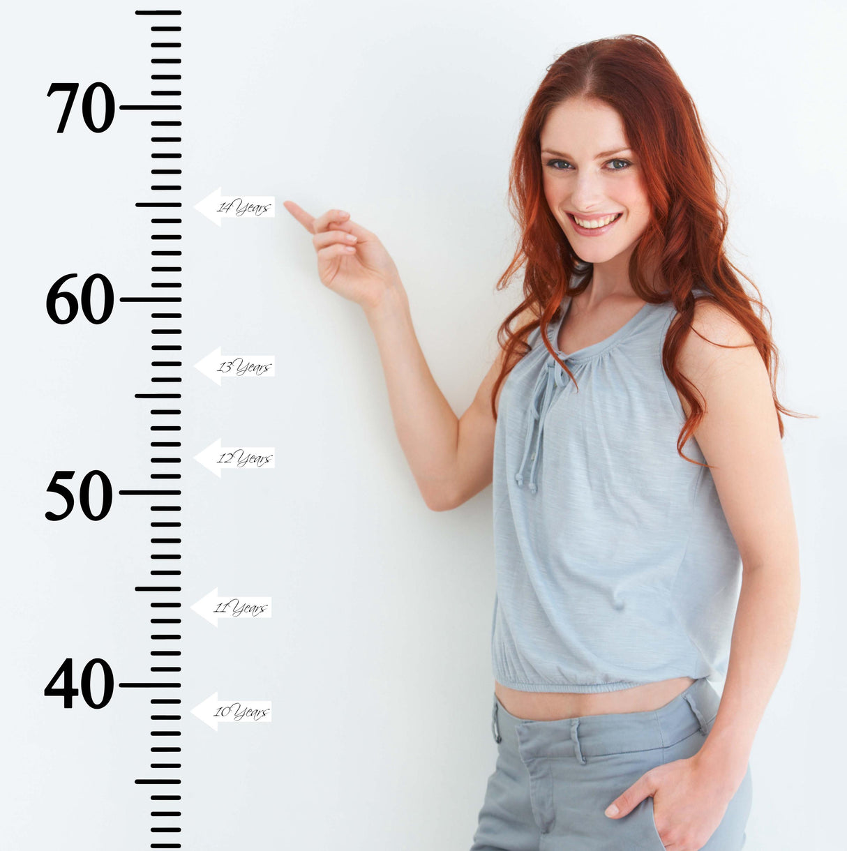 Woman pointing at a growth chart ruler vinyl wall decal measuring child height in inches.