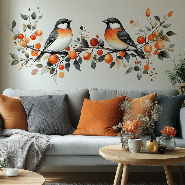 Autumn bird wall decal featuring two birds and orange berries above a cozy couch with orange and gray cushions.