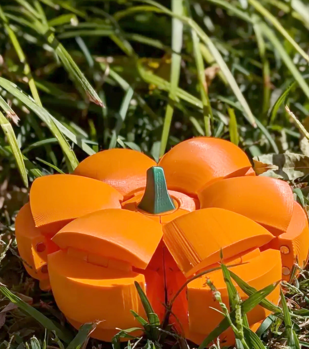 3D-printed Smack O'Lantern candy bowl lying in grass, vibrant pumpkin design for Halloween treats.