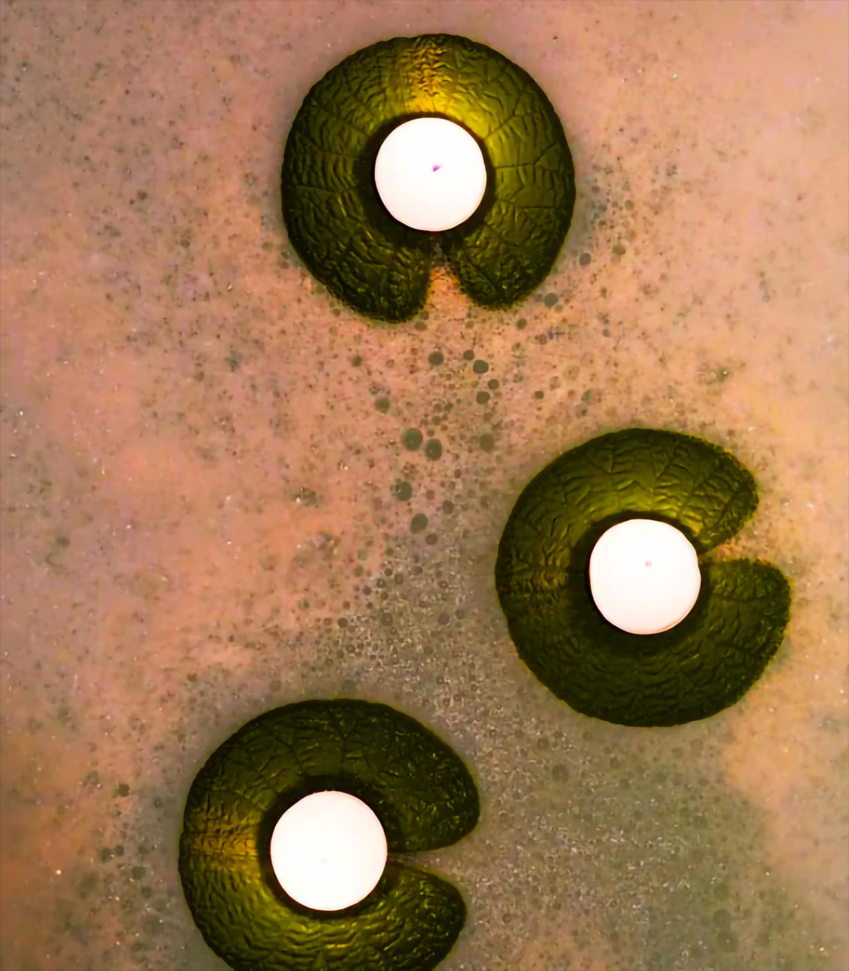 Floating candle holders in a bathtub, creating a spa atmosphere with soothing bubbles and light.