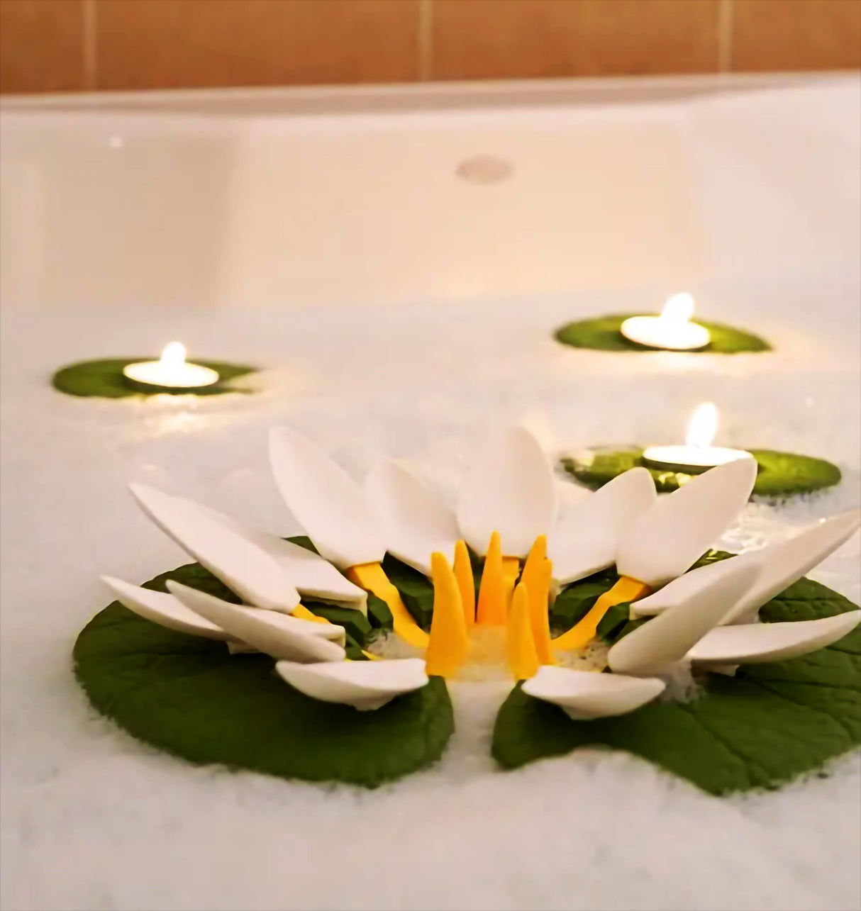 Floating lily pad candle holders in a bathtub, enhancing spa ambiance with tea lights and decorative flowers.