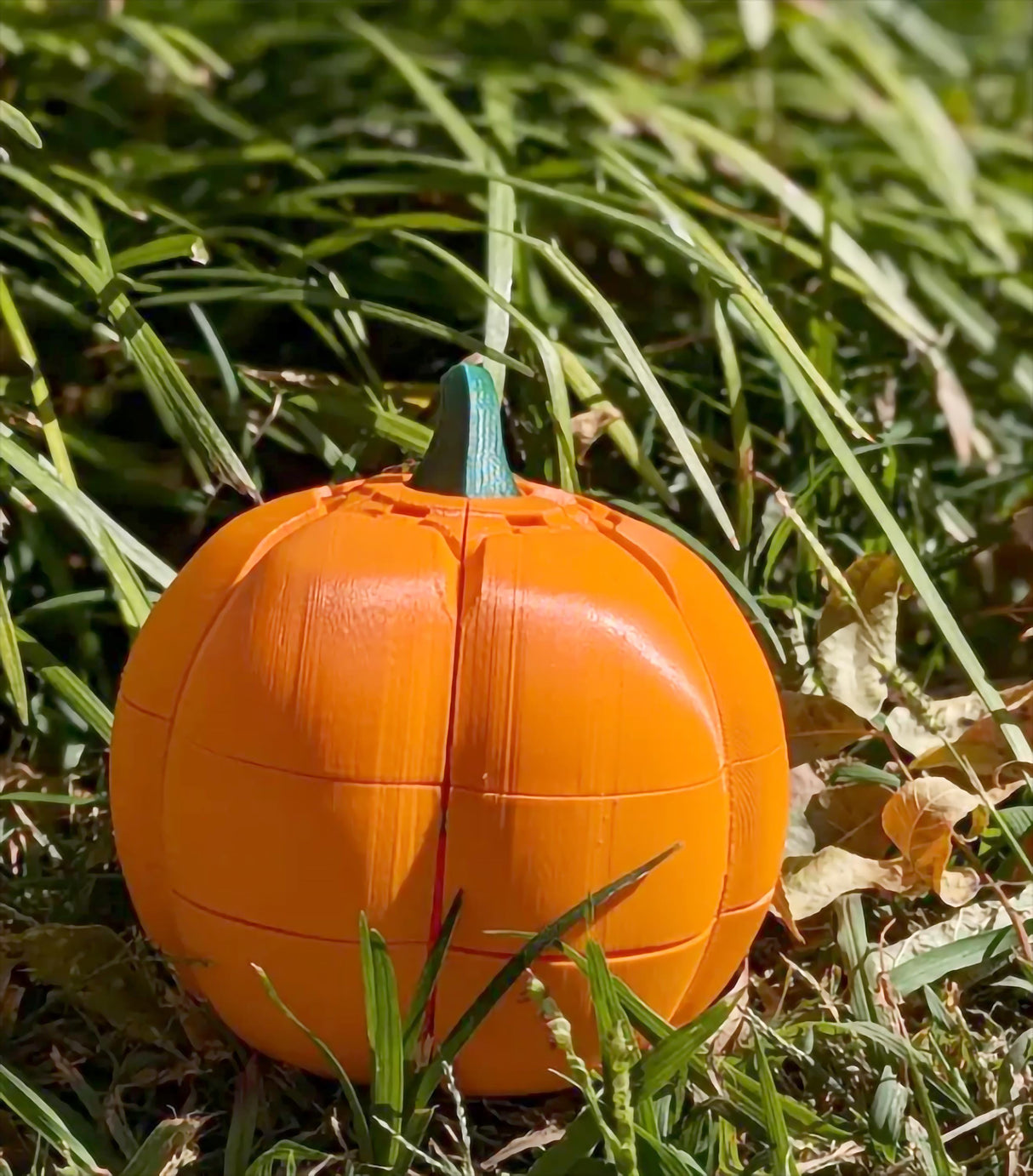3D-printed orange pumpkin candy holder in grass, designed for Halloween treats and festivities.
