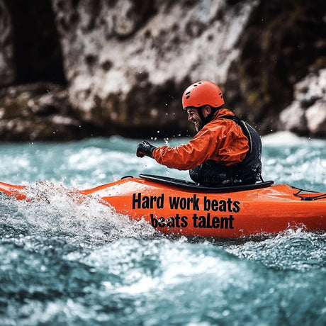 Person kayaking in turbulent water, wearing an orange helmet and jacket, with a motivational phrase on the kayak.