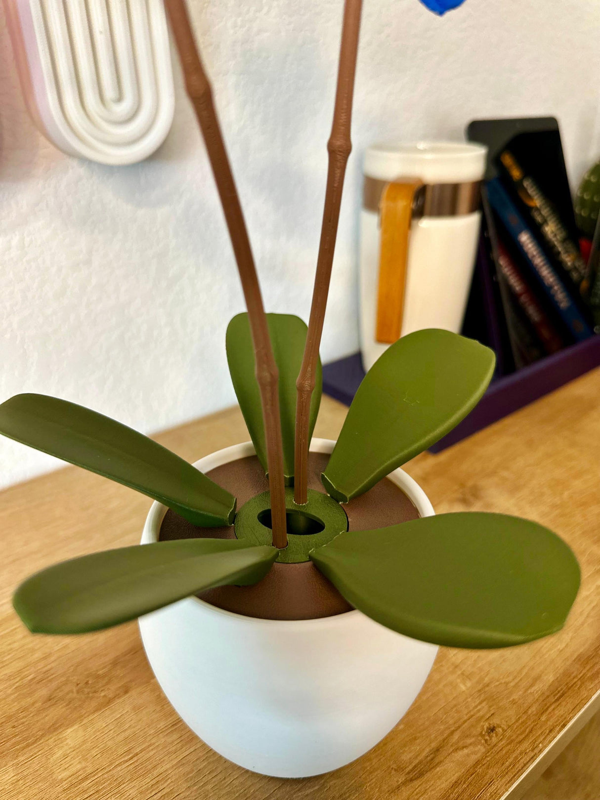 Aromatic Orchid Oil Diffuser and Incense Holder with green leaves in a decorative pot on a wooden surface.