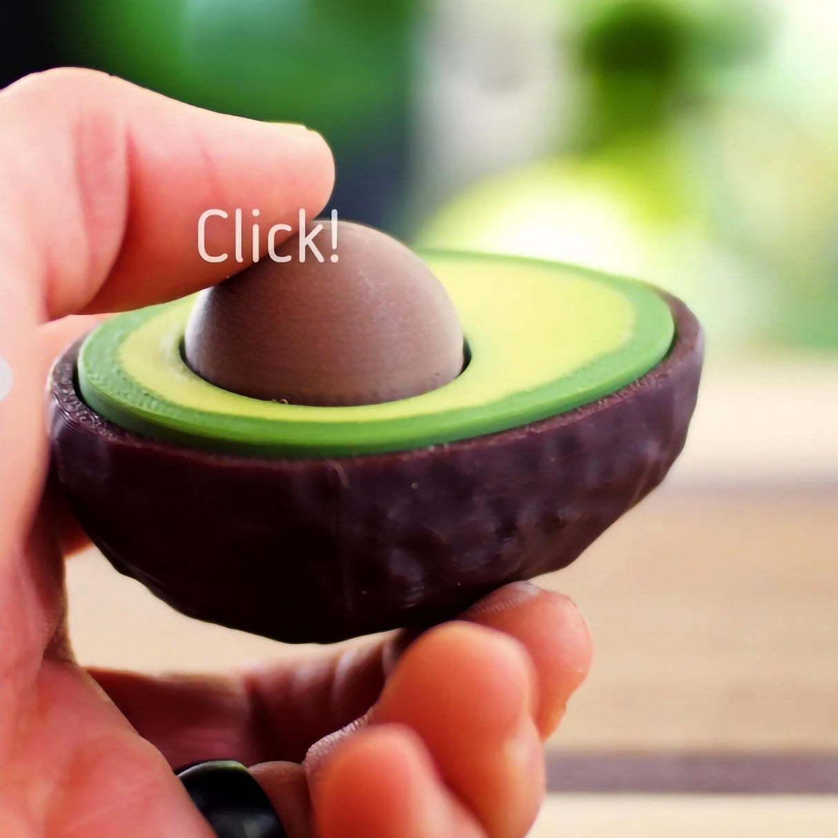 Person holding an avocado-shaped clicker fidget toy for stress relief and fun.