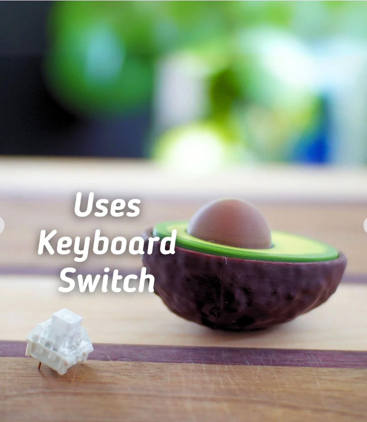 Avocado Clicker fidget toy on wooden surface, showcasing its realistic design and keyboard switch feature.
