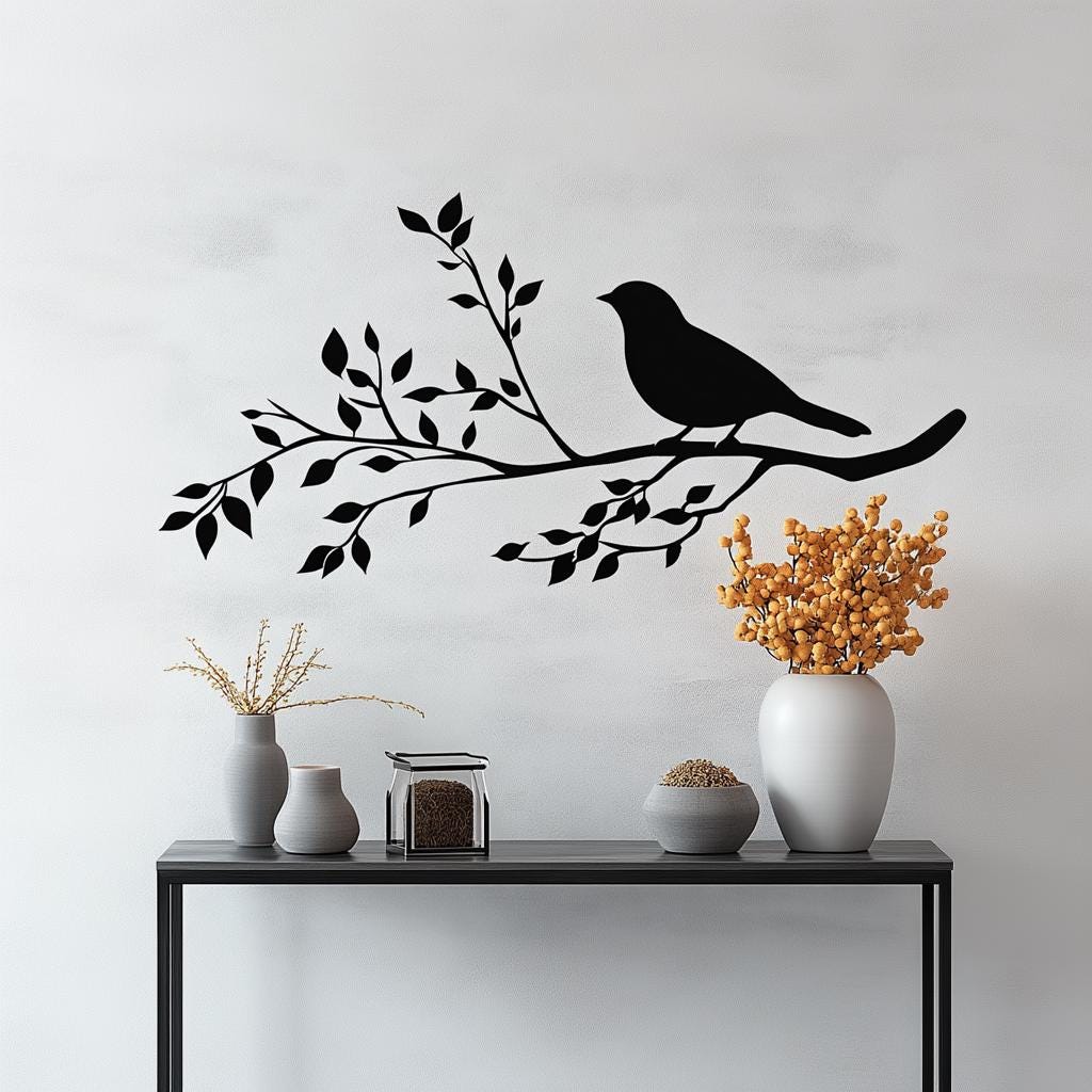 Black bird silhouette on a branch wall decal above a modern shelf with vases and dried flowers.