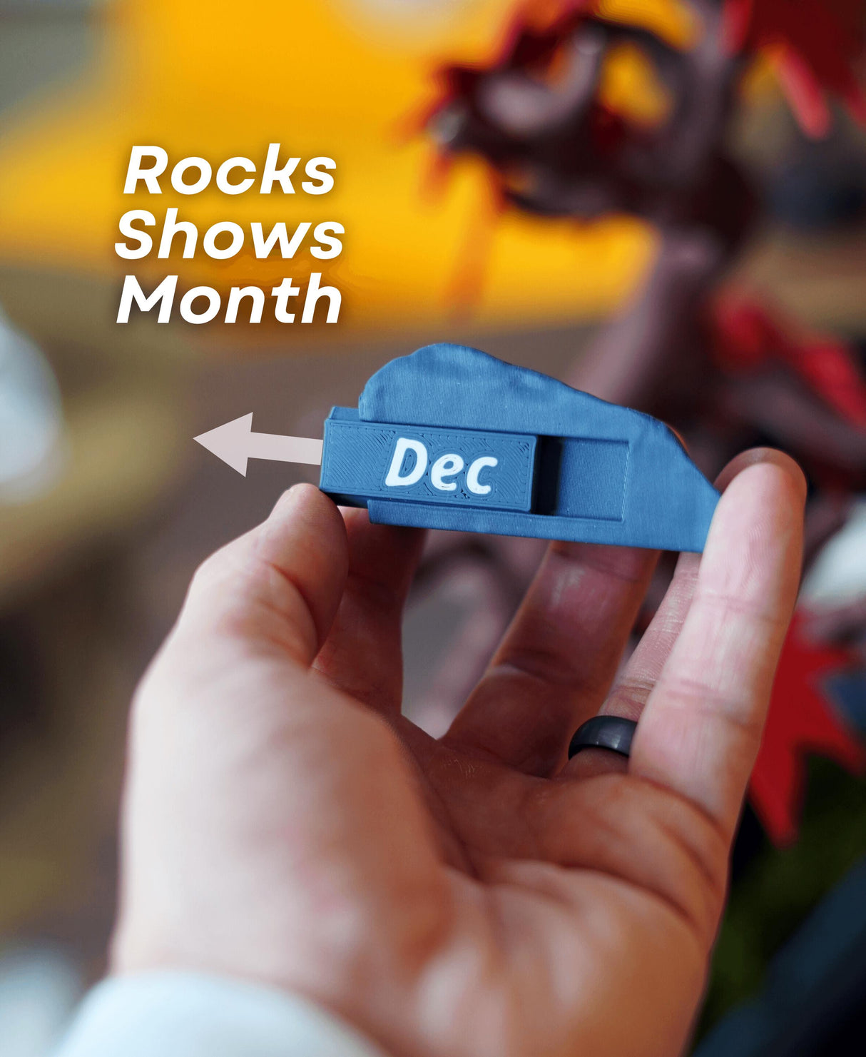 Hand holding a rock marker displaying 'Dec' for the Bonsai 365 Tree Calendar month.