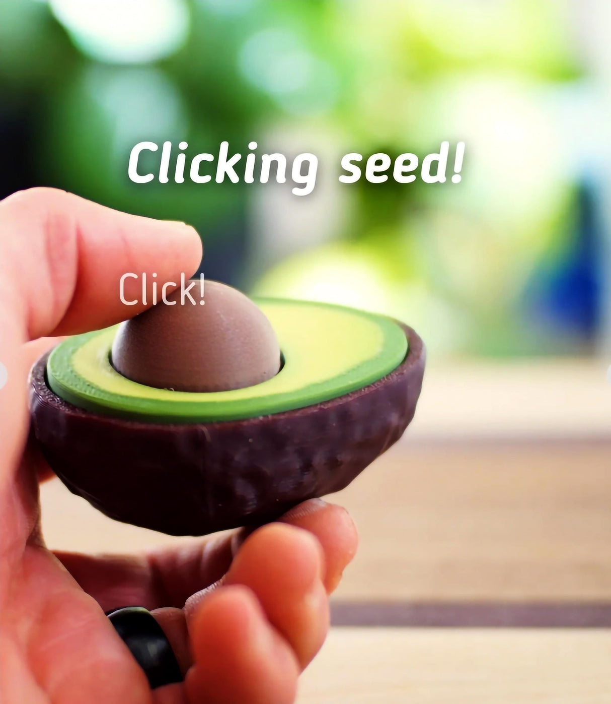 Person holding an avocado clicker fidget toy with a clickable seed for stress relief.