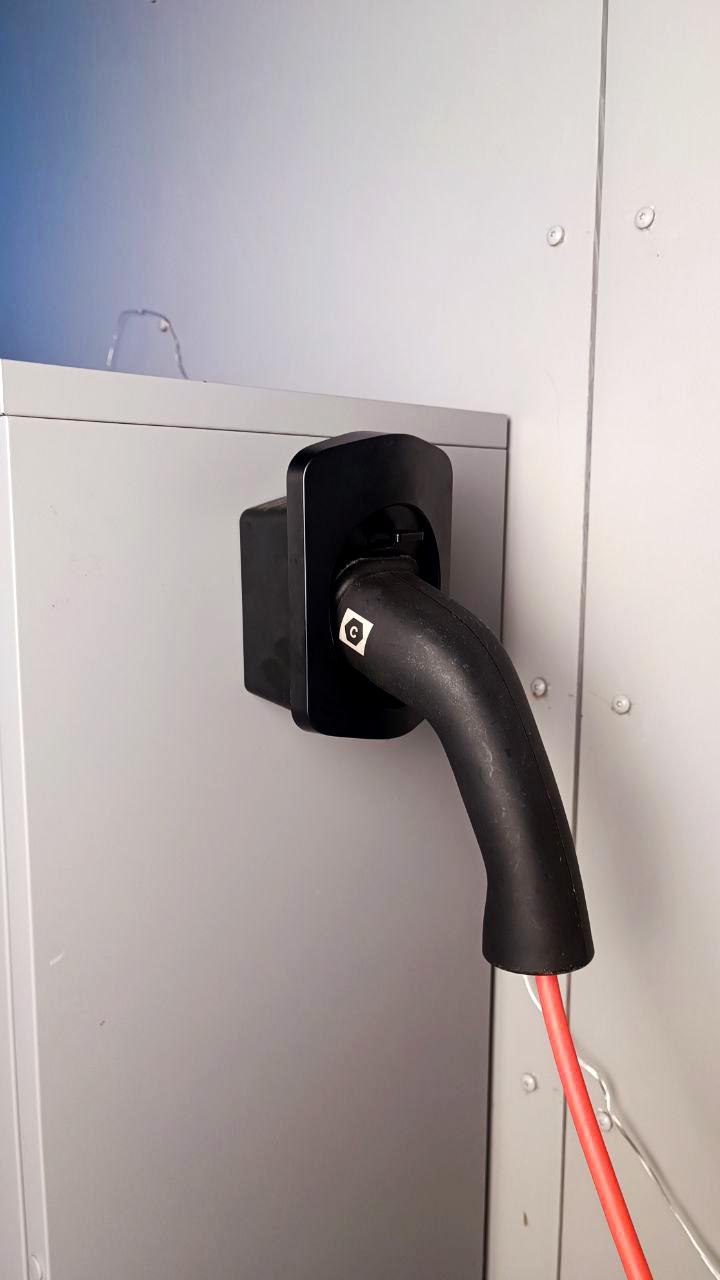 Wall-mounted electric car charger connector holder with charging cable neatly stored.