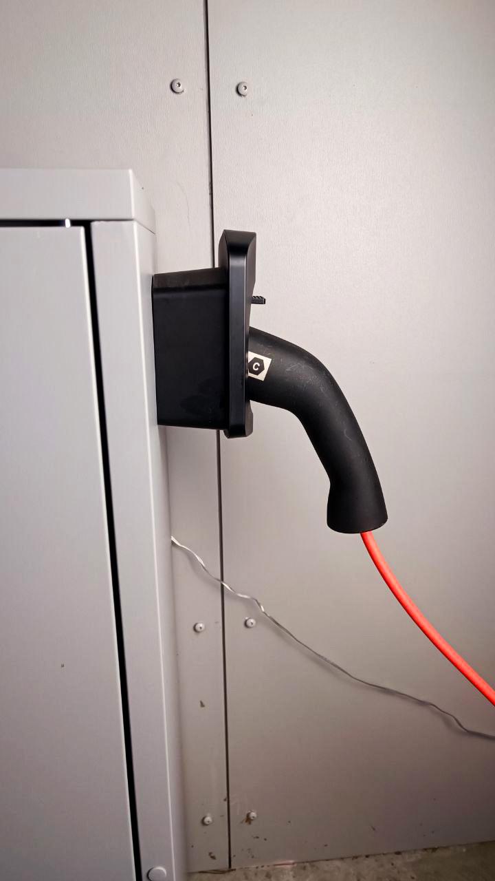 Electric car charger connector mounted on wall, showcasing a tidy EV charging area with cable management.
