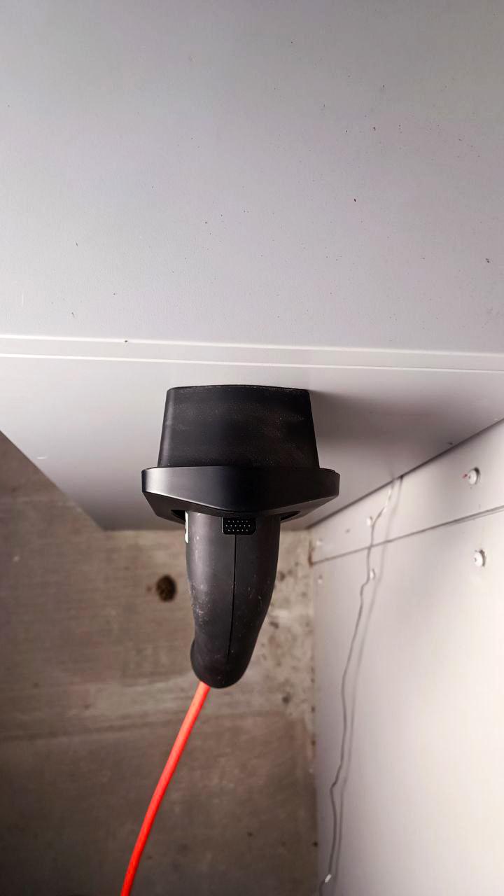 Electric car charger connector holder mounted on a wall, showcasing the charging cable neatly stored.