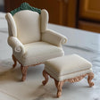 1:12 scale Victorian armchair and ottoman set with intricate details and curved legs in soft white upholstery.
