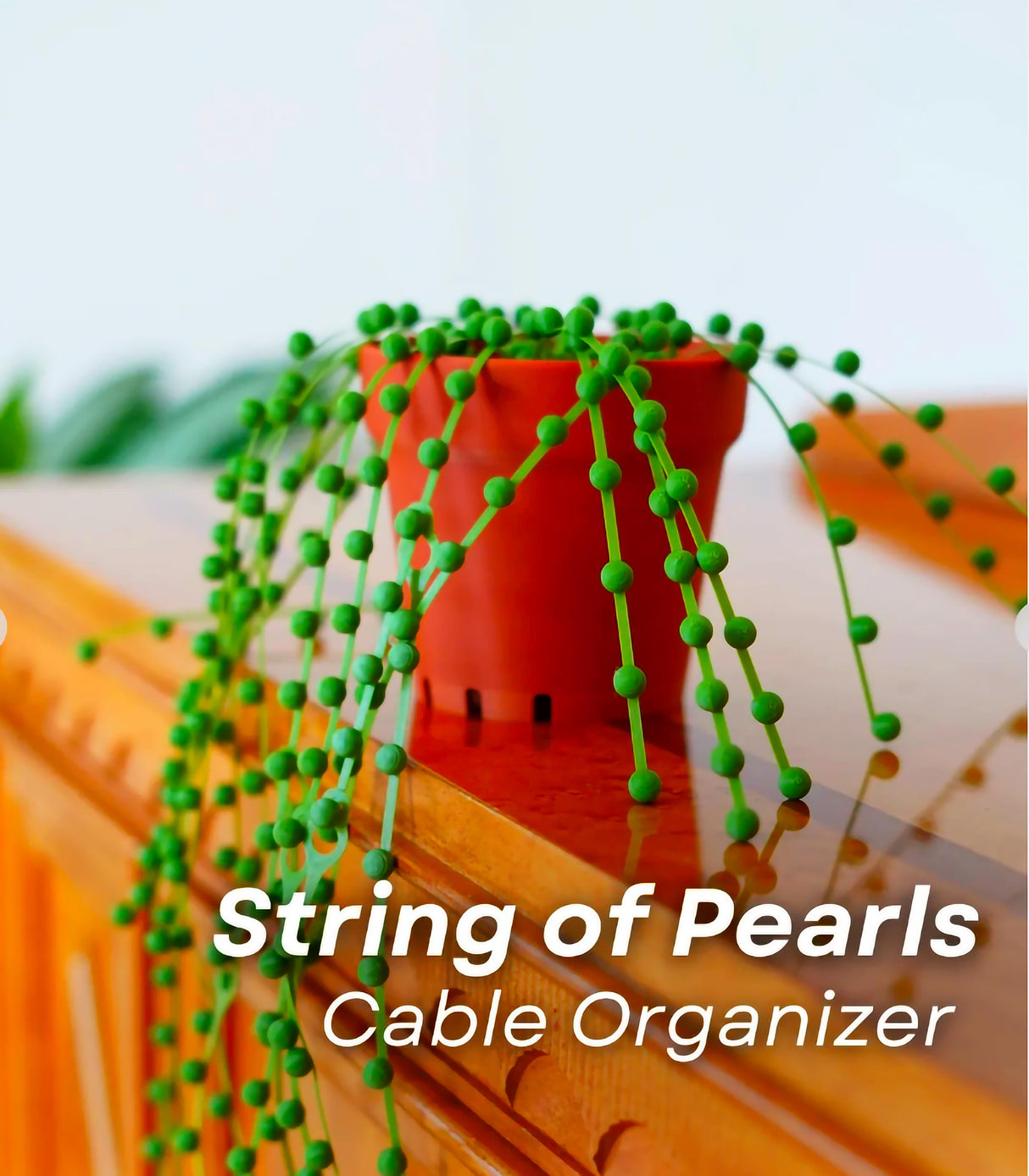 String of Pearls cable organizer with green beads cascading from a pot, enhancing desk decor and cable management.