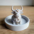 3D-printed Highland cow jewelry dish with a ring, rustic trinket tray for jewelry organization.