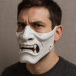 White Oni samurai mask worn by a man, showcasing bold features and detailed craftsmanship for cosplay or Halloween.