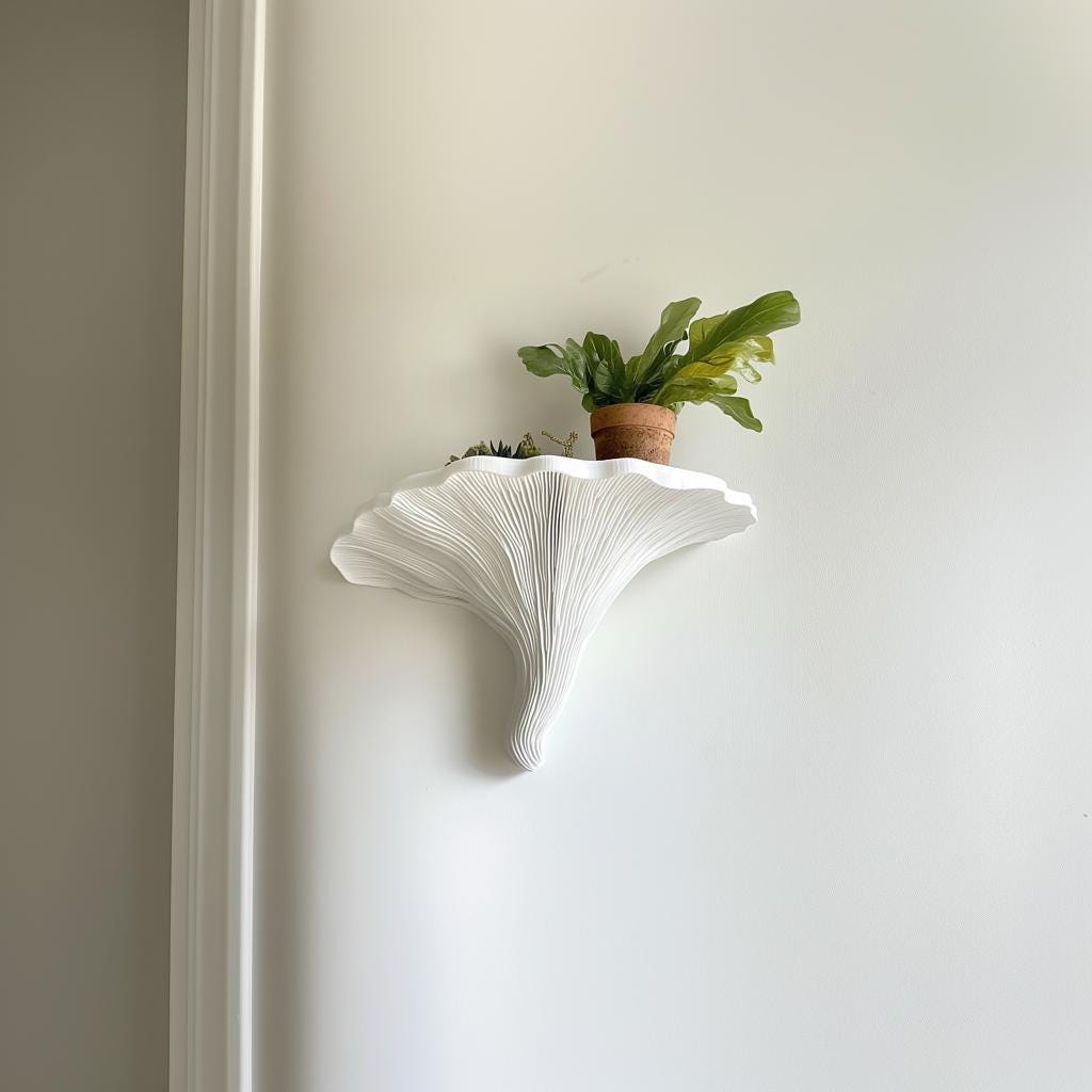 Sculptural Turkey Tail mushroom wall shelf in matte white, holding a potted plant against a light wall.