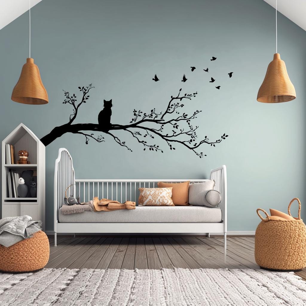 Vinyl wall decal of a cat sitting on a tree branch with flying birds, cut in solid black and applied to a pale green wall above a child's bed in a cozy, modern nursery.