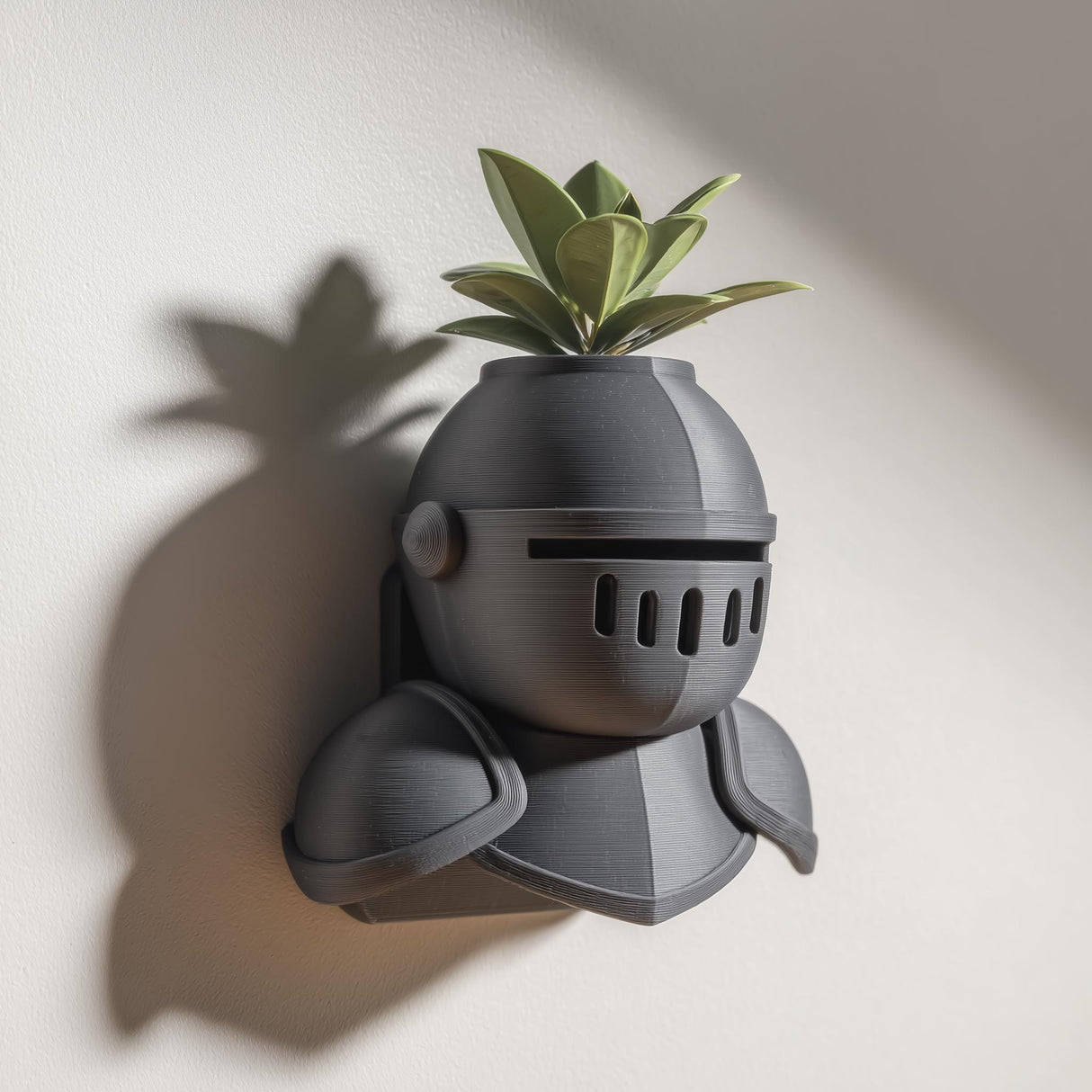 3D printed wall mounted knight helmet planter shelf with a small green plant, displayed on a light wall with soft natural shadows.