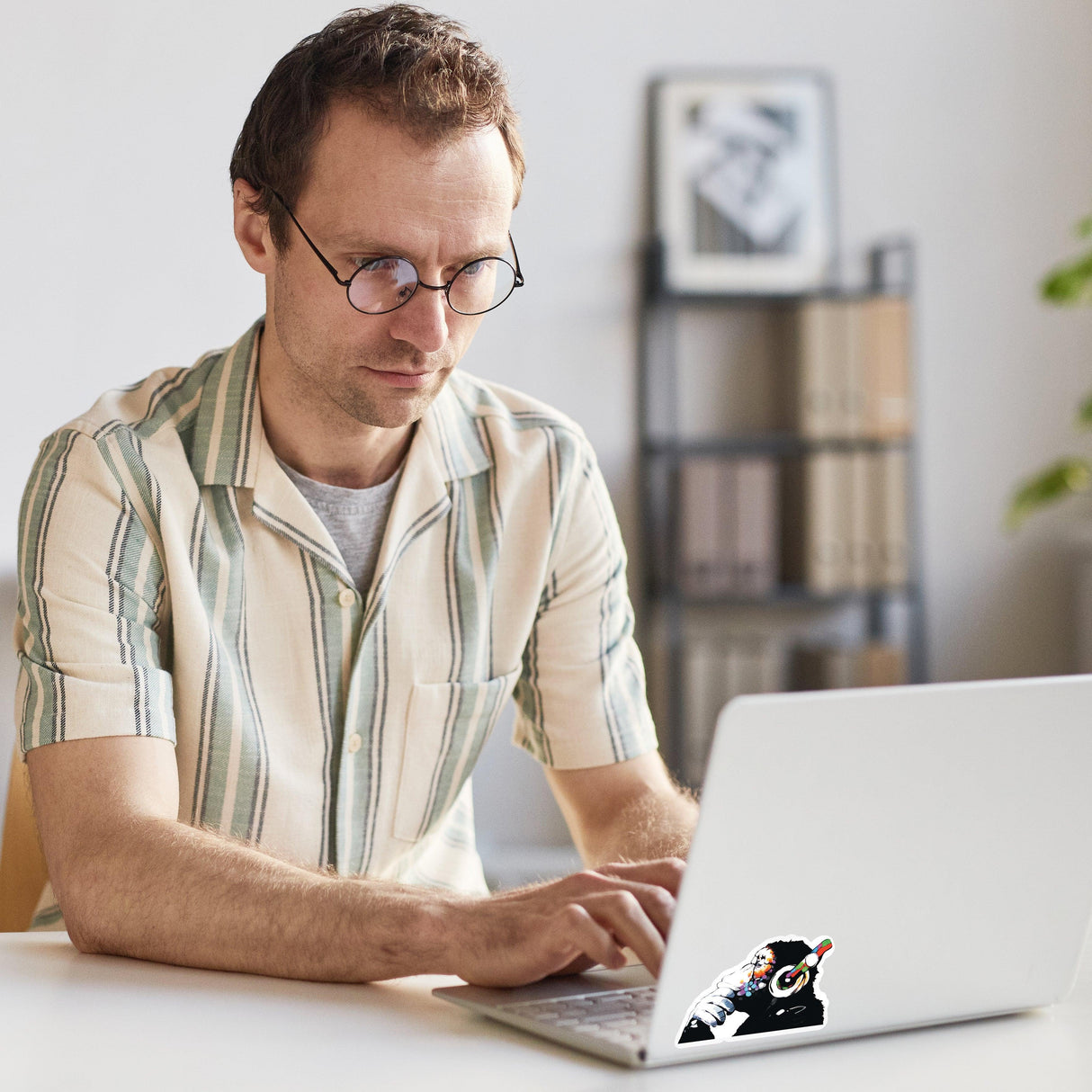 Man with glasses using laptop featuring a Music Monkey vinyl sticker decal on the side.