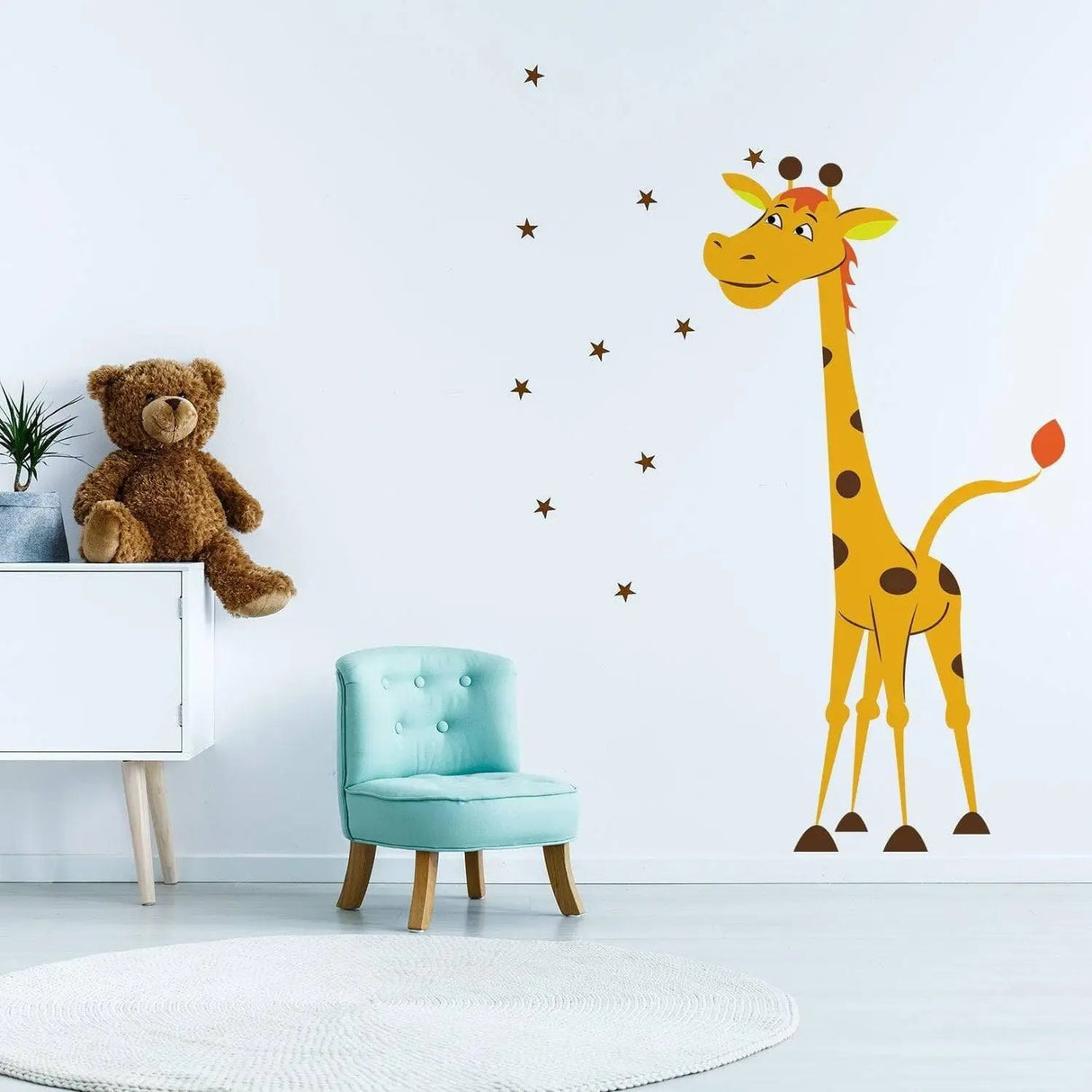 Cute giraffe wall decal in a nursery with a teddy bear and blue chair, perfect for kids' decor.