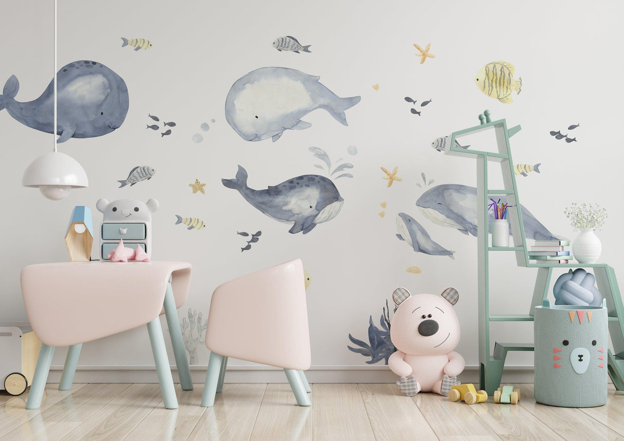 Undersea themed wall decals featuring whales and fish in a child's room with pastel furniture.