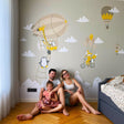 Family enjoying adorable animal wall stickers featuring penguins and balloons in a cozy children's room.