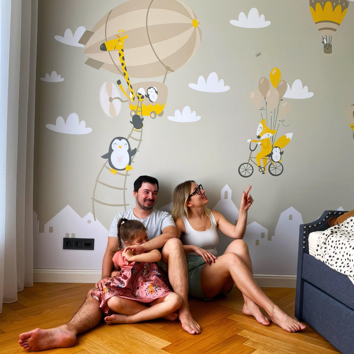 Family enjoying adorable animal wall stickers with penguins and balloons in a child's room decor.