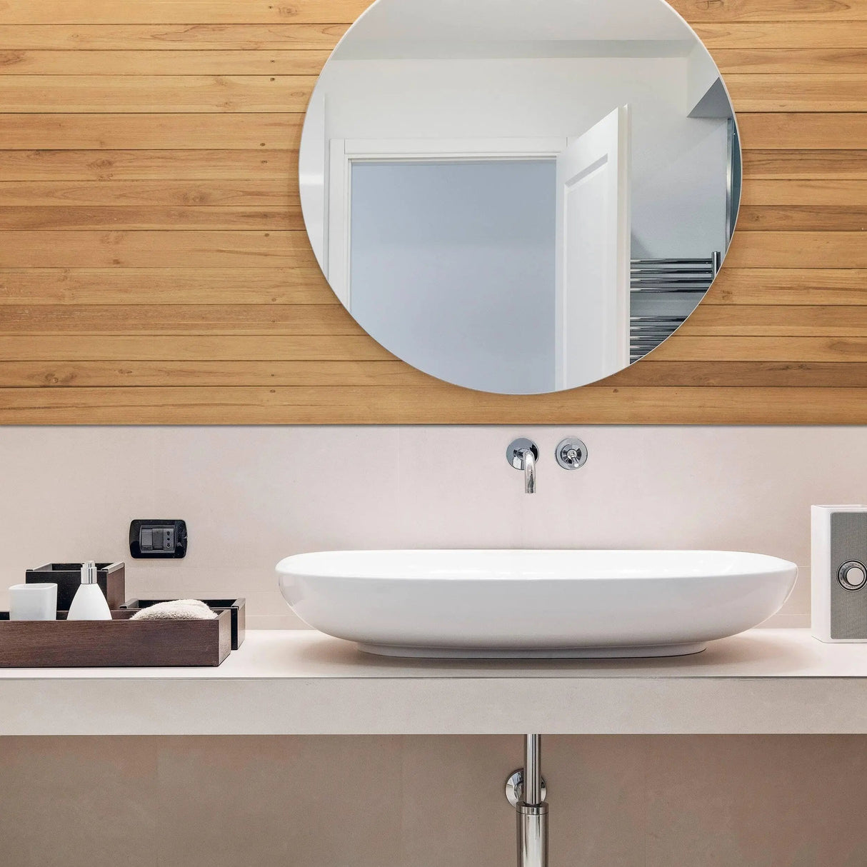 Modern bathroom featuring round mirror and white oval sink with rustic wood wall and minimal decor.