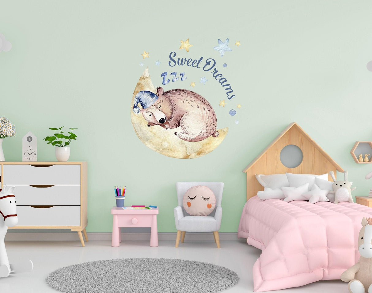Sleeping animal wall sticker in kids room, featuring a cozy bear on a moon with 'Sweet Dreams' text.