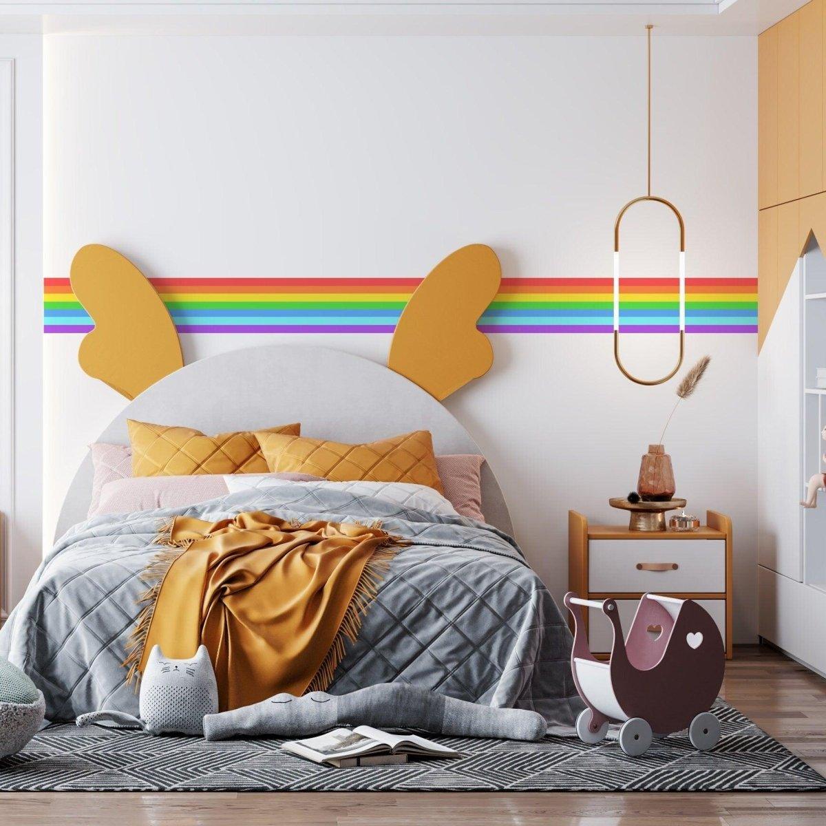 Colorful rainbow stripe vinyl decal on wall above a cozy bedroom with a stylish bed and playful decor.