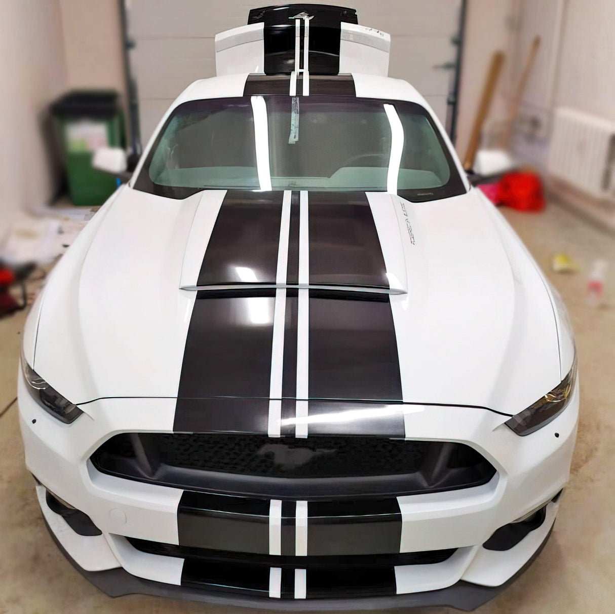 Stylish car with black racing stripes decals showcasing a sleek, upgraded look in a garage setting.
